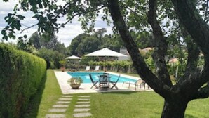A backyard with a swimming pool, a paved pathway, and outdoor furniture.