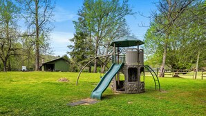 A playground with a slide, climbing structure, and a covered area.