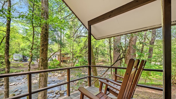 A wooden deck with a railing overlooking a river, surrounded by trees.