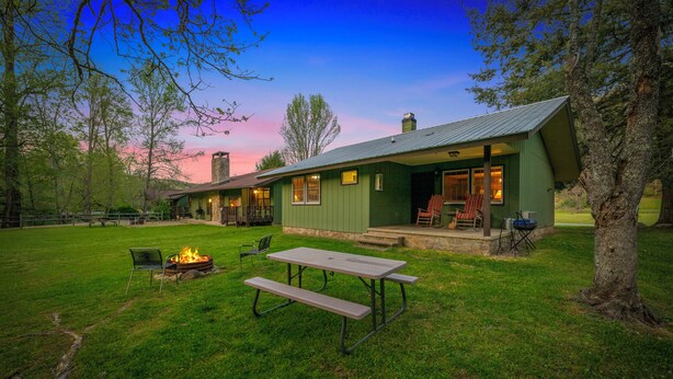 A green building with a patio area, a fire pit, and a picnic table. - Riverside Cabin, minutes to Downtown Gatlinburg! Includes tickets to Dollywood, Anakeesta, (Sevierville)