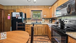 A kitchen with wooden cabinets, a stainless steel refrigerator, a microwave, and a stove. - Riverside Cabin, minutes to Downtown Gatlinburg! Includes tickets to Dollywood, Anakeesta, (Sevierville)
