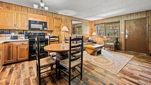 A kitchen with wooden cabinets, a microwave, and a dining area with chairs and a table. - Riverside Cabin, minutes to Downtown Gatlinburg! Includes tickets to Dollywood, Anakeesta, (Sevierville)
