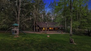A cabin with a wooden exterior, surrounded by a grassy yard and trees. - 3 Bedroom 2.5 miles from Rocky top sports complex (Sevierville)