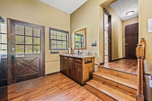 A wooden staircase leading to a second floor, a kitchen area with a countertop and cabinets, and a door with a window.