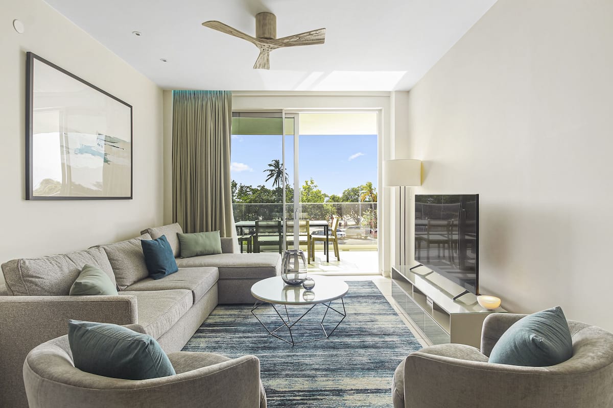 A modern living room with a sofa, armchairs, a coffee table, and a TV.
