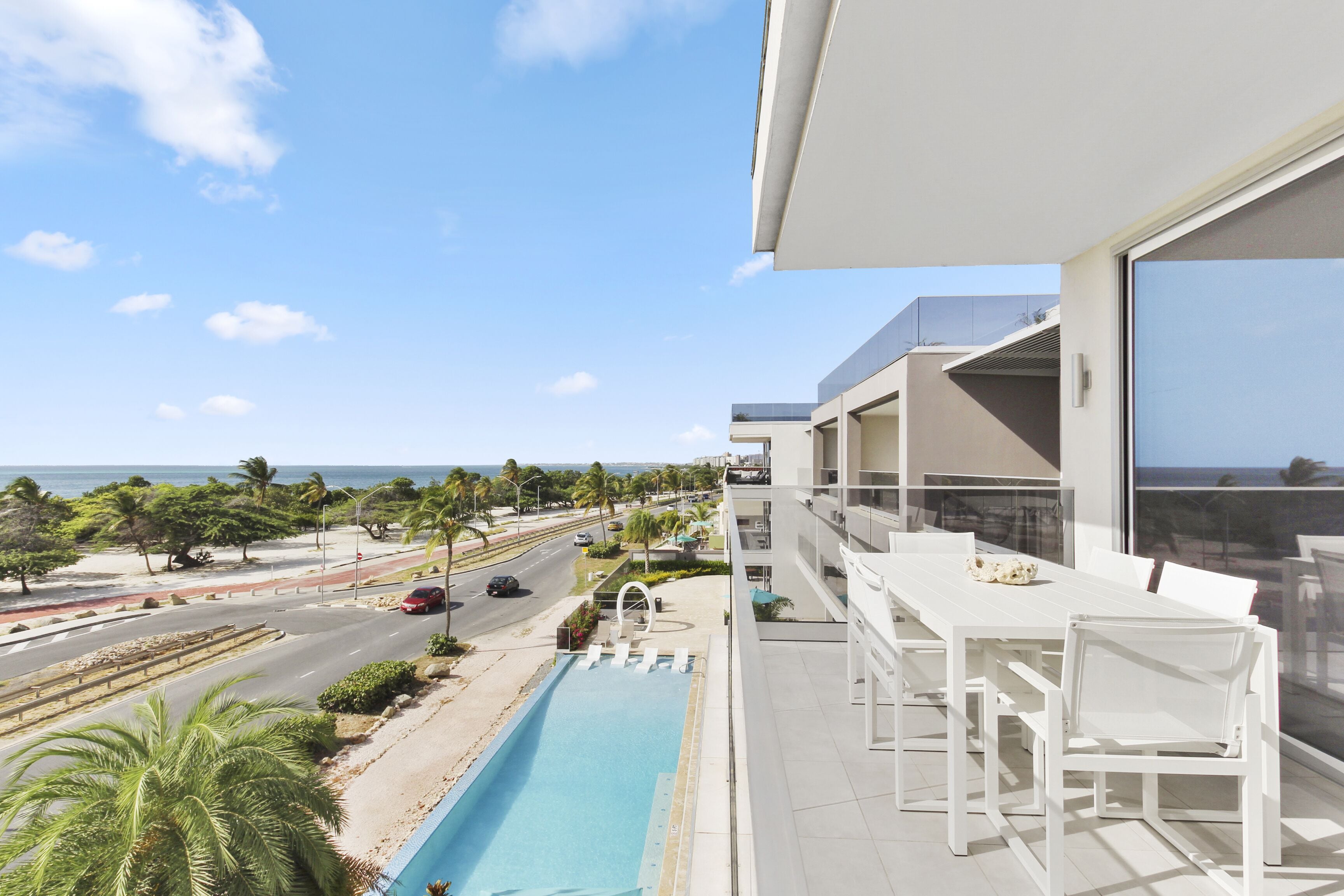 A modern building with a pool, outdoor seating, and a view of the ocean.