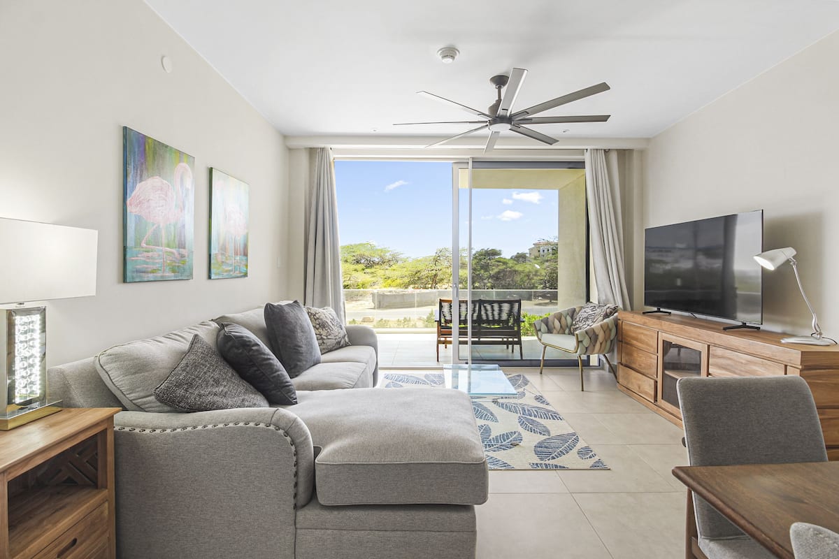 A modern living room with a sofa, TV, and a view of the outdoors.