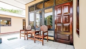 A room with a wooden table and chairs, a large window with a view, and a door with a metal grill. - OYO 91053 Desa Wisata Gilimanuk (Malang)