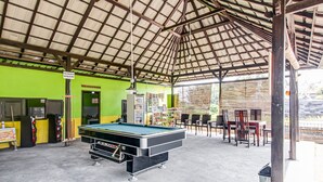 A covered recreational area with a pool table, seating, and a sign indicating a billiards area. - OYO 91053 Desa Wisata Gilimanuk (Malang)