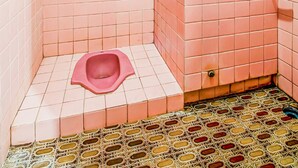 A small bathroom with pink tiles, a pink toilet, and a patterned floor. - OYO 91053 Desa Wisata Gilimanuk (Malang)