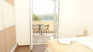 Habitación de hotel con cama, una pequeña mesa con sillas y vistas a un balcón con mesa y sillas.