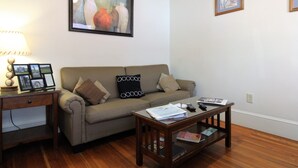A living room with a sofa, a coffee table, a lamp, and framed artwork on the wall. - Team Elm (Entire Property) (Oneonta)