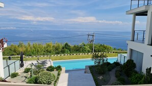A modern building with a pool and a view of the sea.