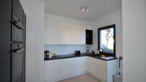 A modern kitchen with white cabinets, a black countertop, and a window providing natural light.