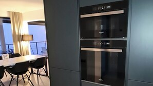 A modern kitchen with a built-in refrigerator and oven, a dining area with a table and chairs, and a view of the outdoors.