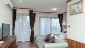 A hotel room with a sofa, a bed, a TV, and a painting on the wall. - Baan Plaifah Khao Yai Hotel (Pak Chong)
