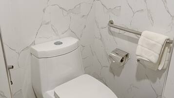 A bathroom with a toilet, a towel rack, and a trash bin.