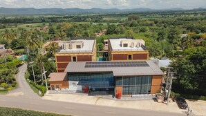 A modern building with a flat roof, solar panels, and a swimming pool. - Baan Plaifah Khao Yai Hotel (Pak Chong)