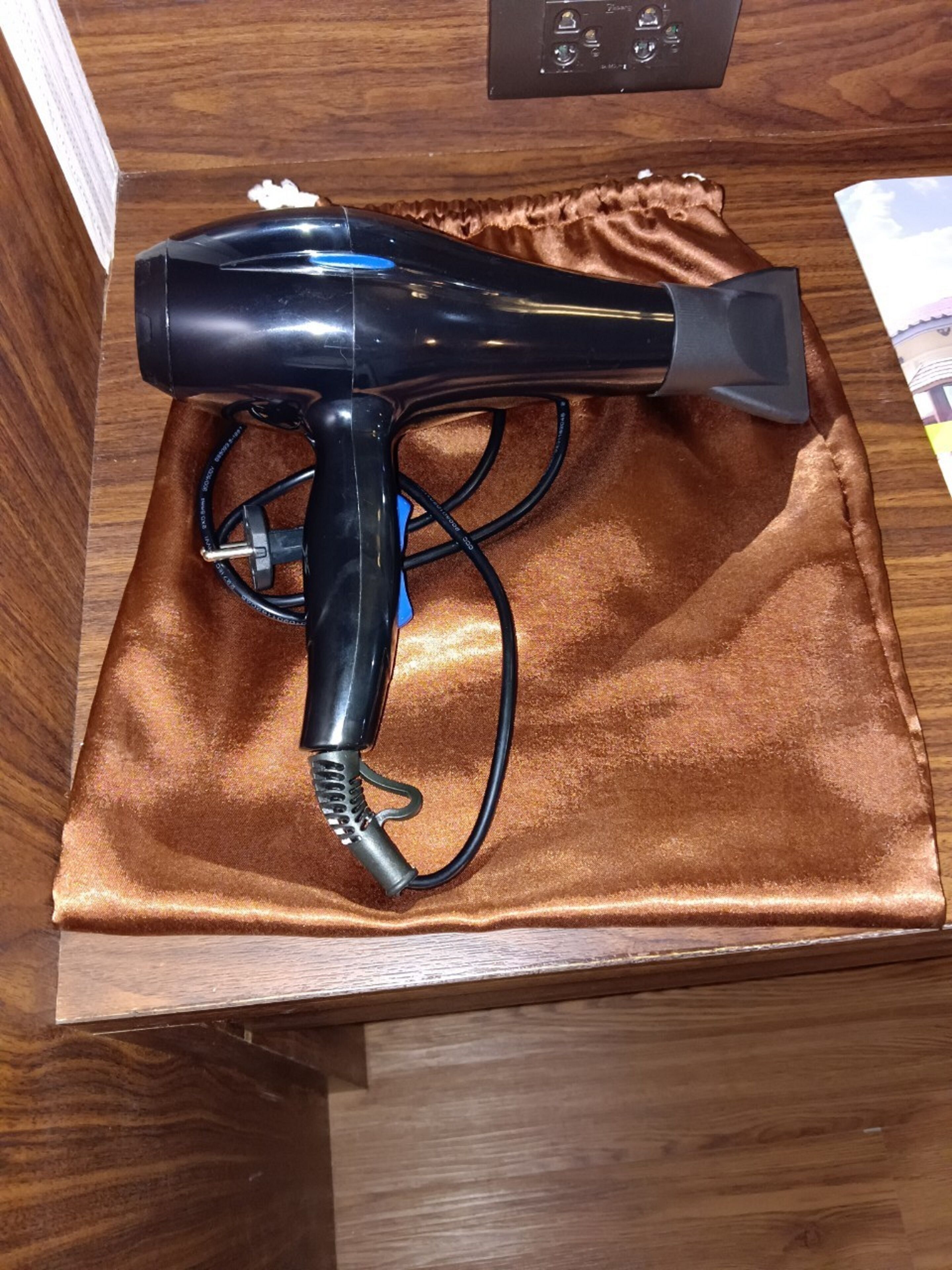 A black hair dryer on a brown satin cloth.