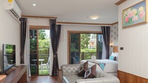 A modern living room with a sofa, a TV, and a balcony with outdoor seating. - Baan Plaifah Khao Yai Hotel (Pak Chong)