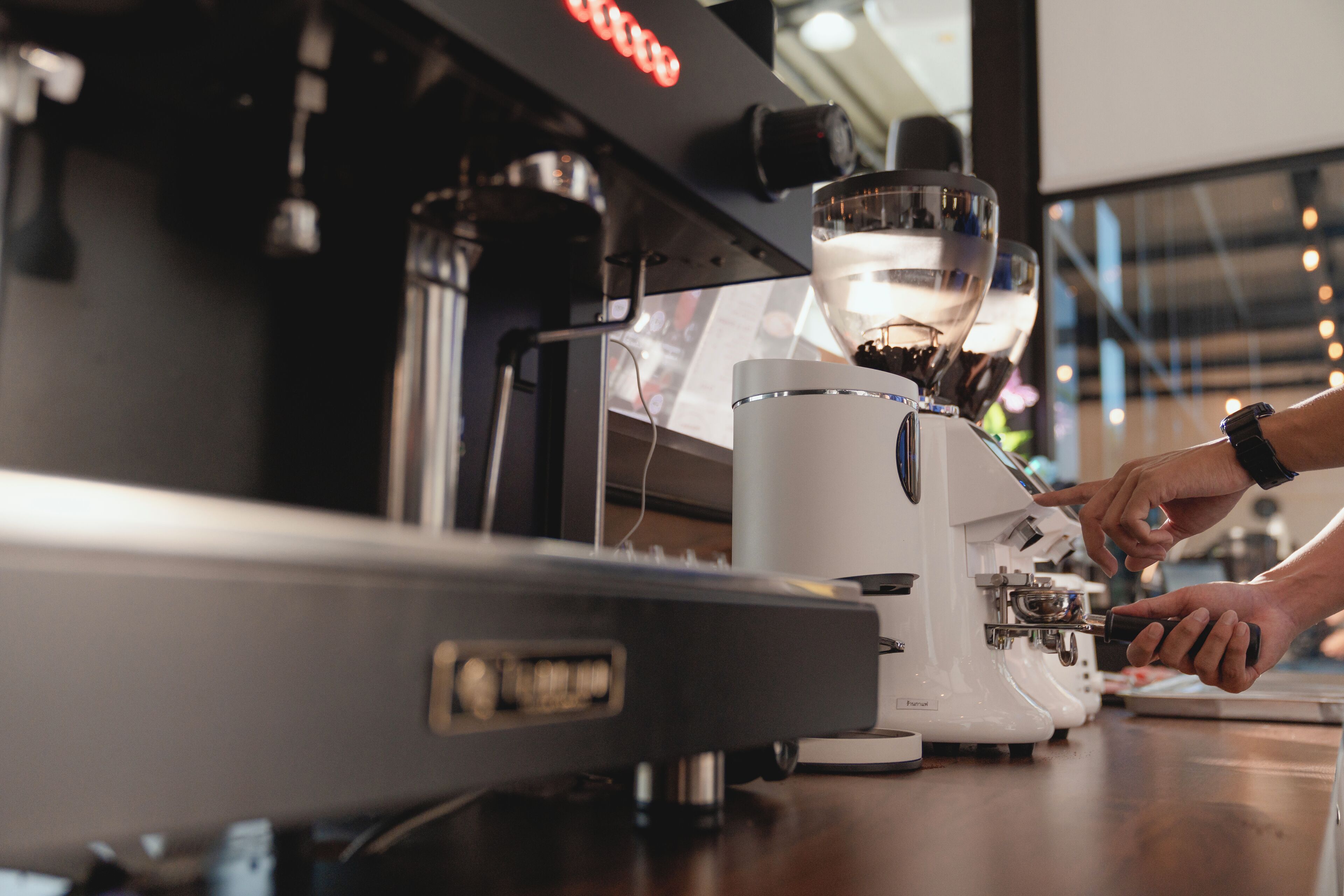 A coffee machine with a digital display and a person operating it.