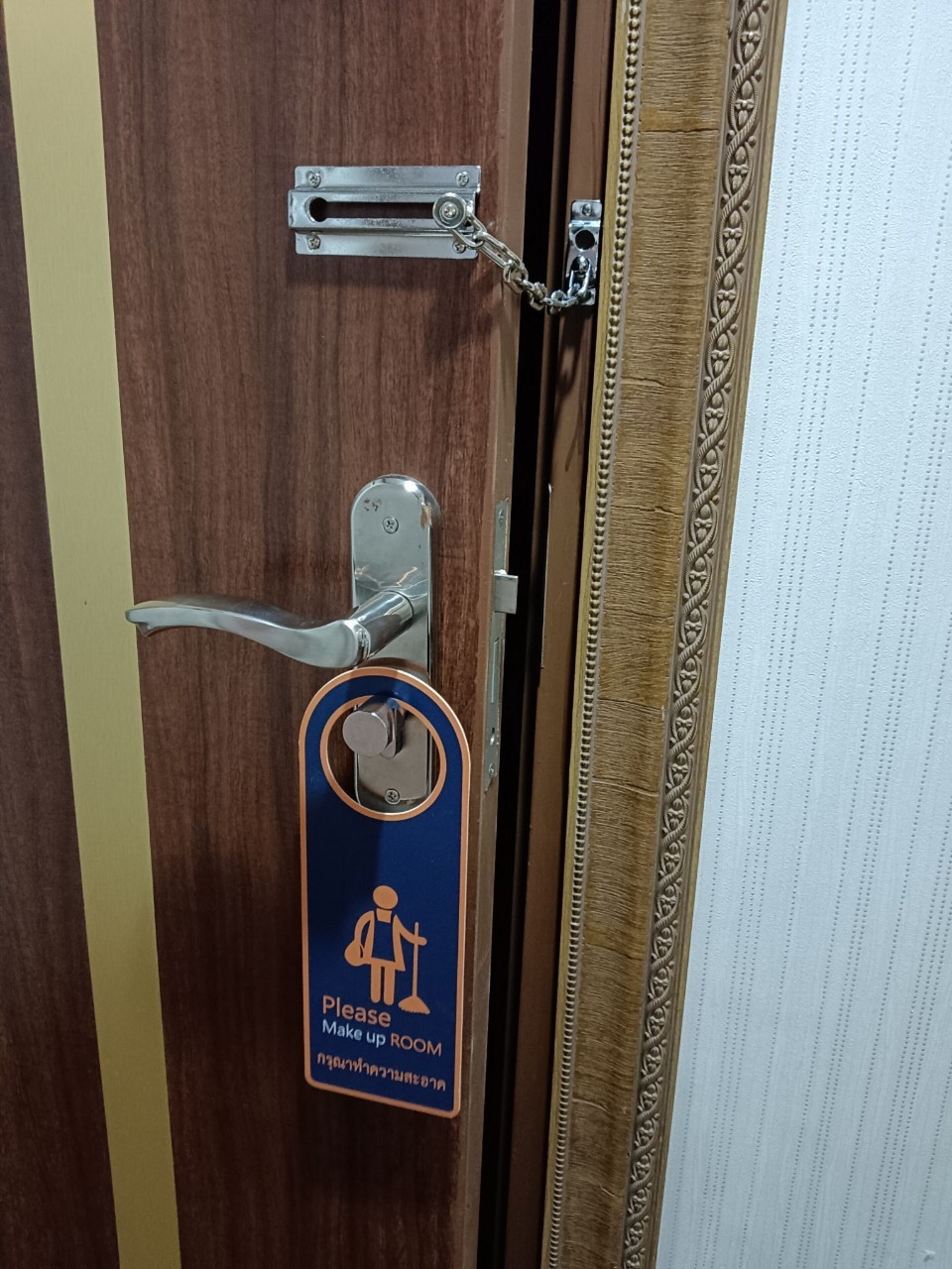 Una puerta con manija de metal, un llavero con un cartel que indica un cuarto de maquillaje, y un marco de madera decorativo.