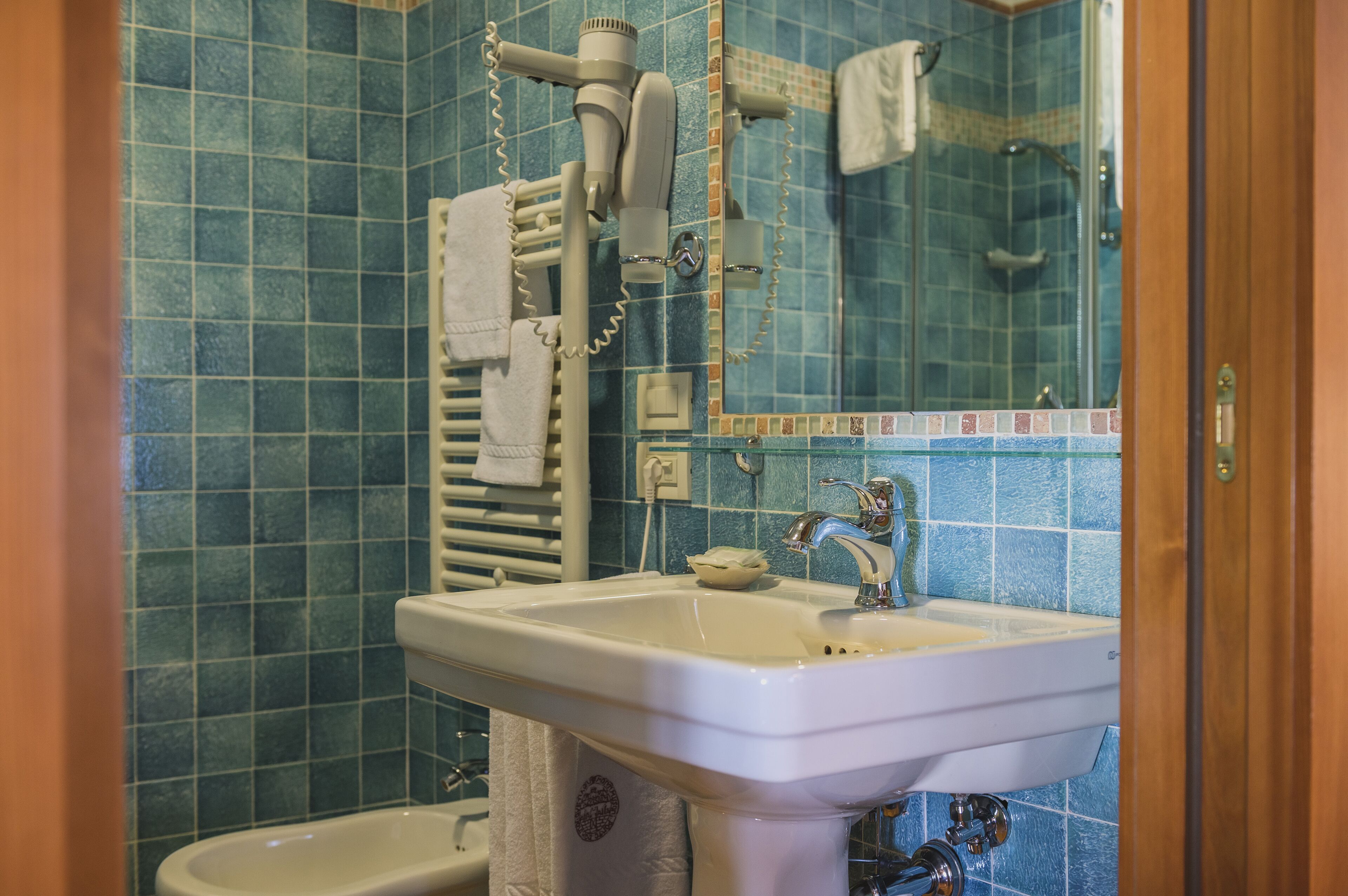 Un baño con lavamanos, espejo y perchero.
