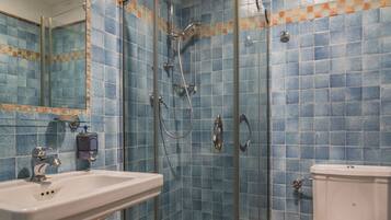 Une salle de bain avec une douche à parois de verre, un lavabo sur colonne et des toilettes.