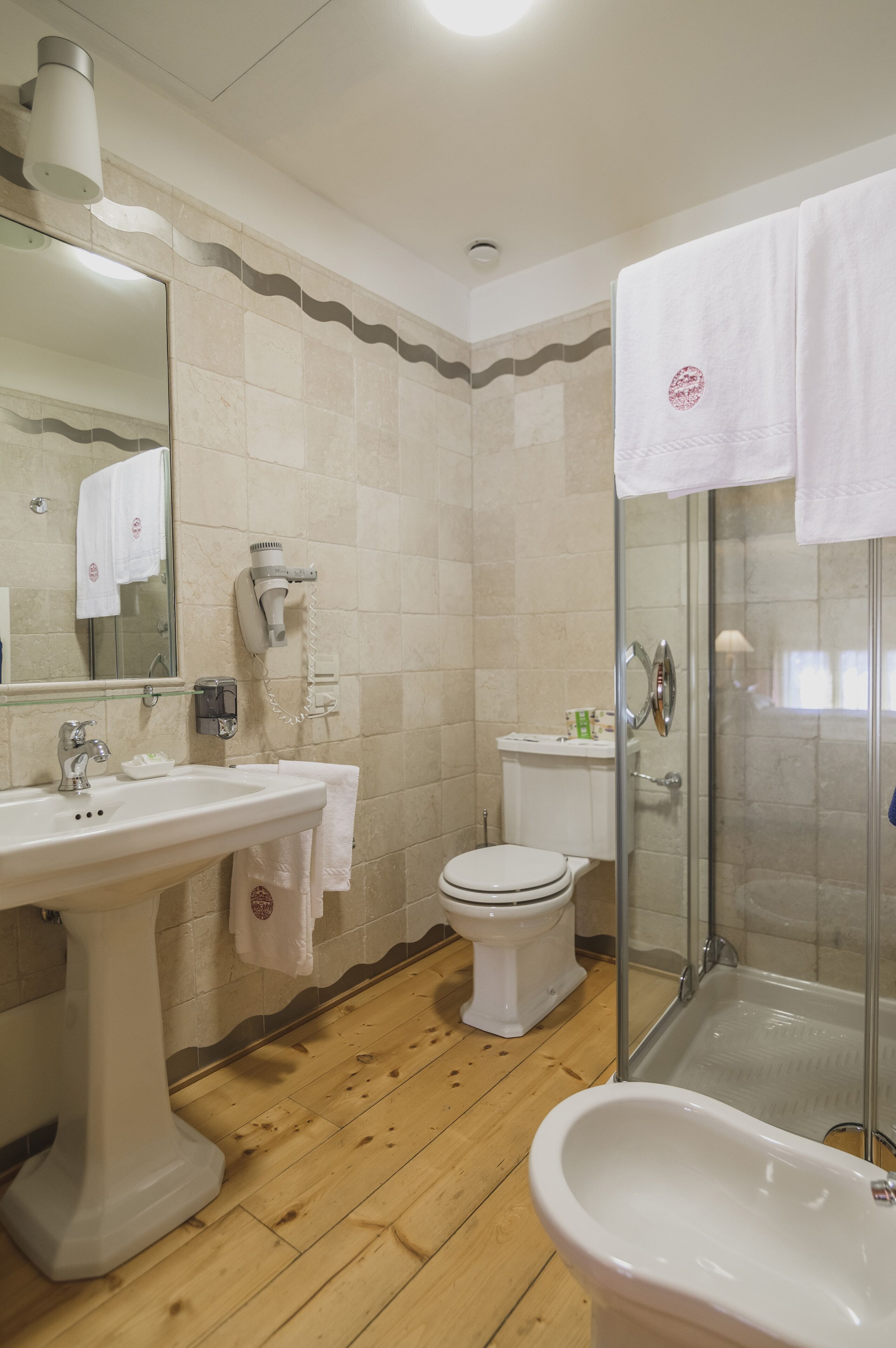 Baño con lavamanos, inodoro y cabina de ducha.