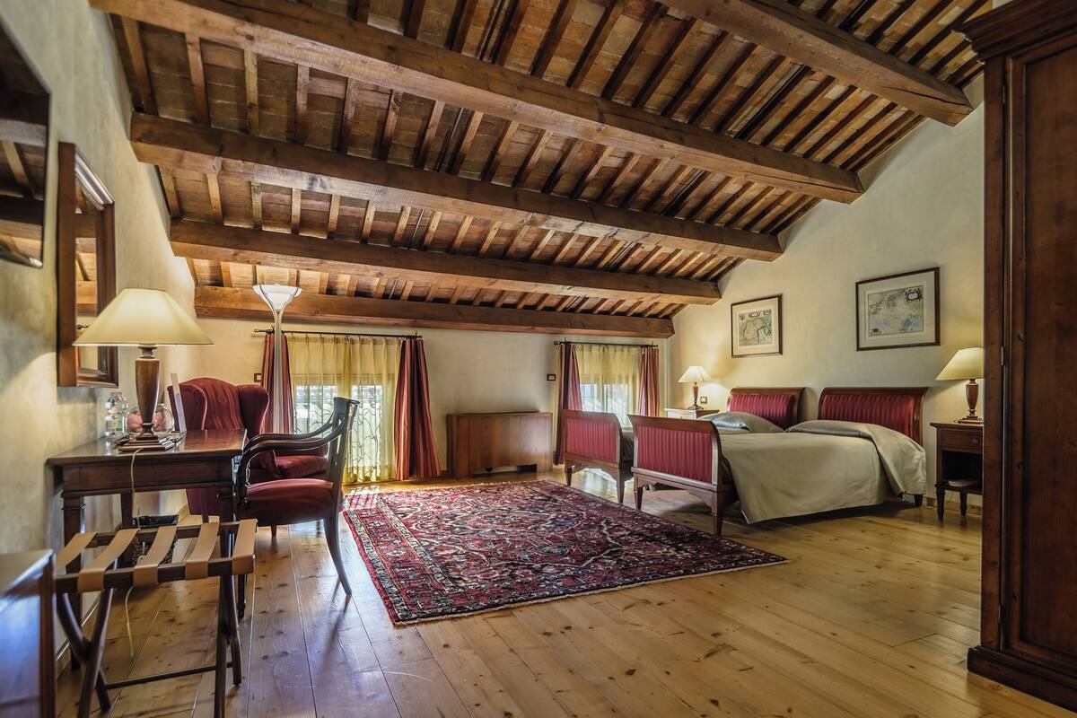 Een kamer met houten plafond, een bed, een bureau en een stoel.