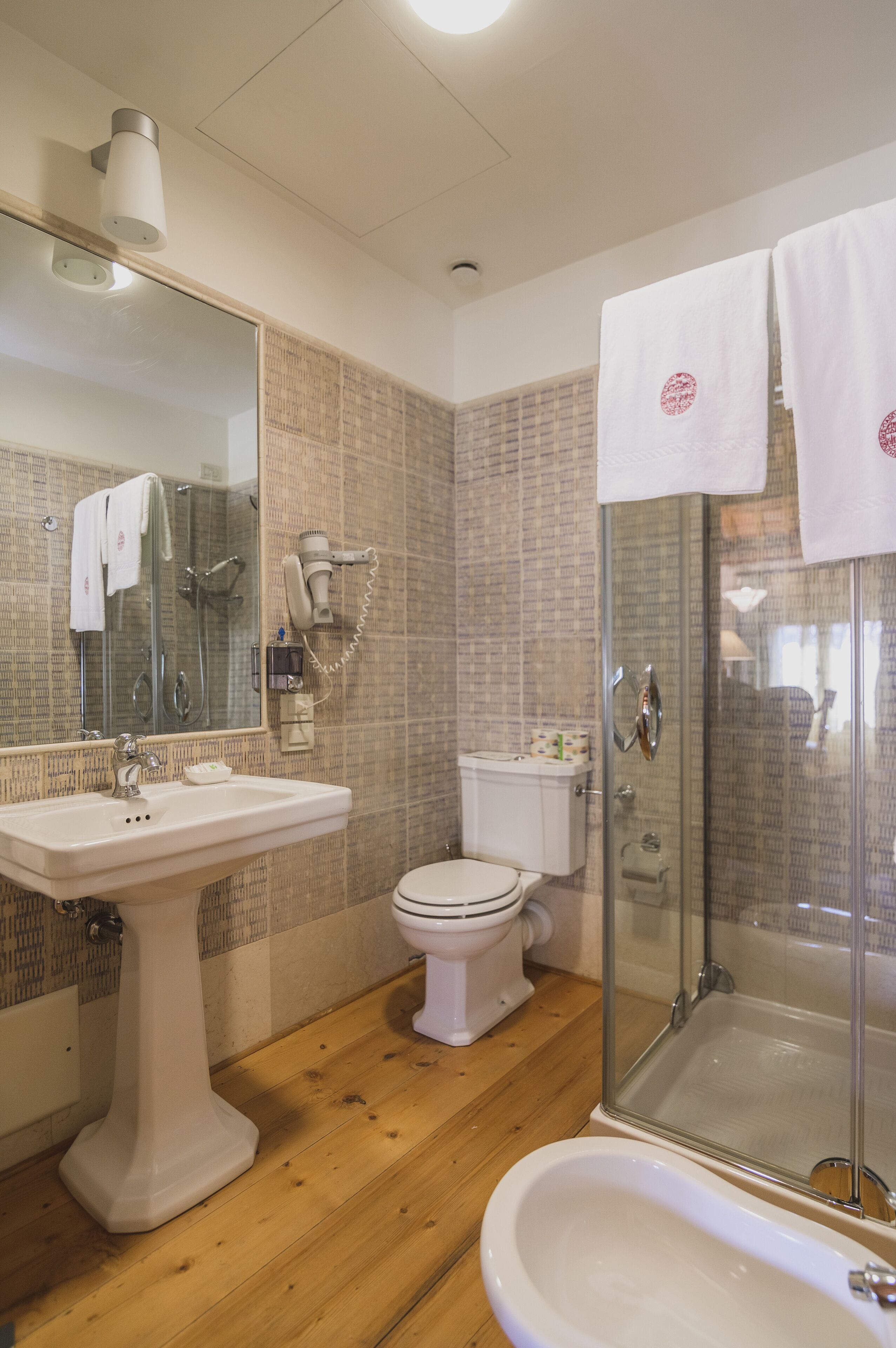 Un baño con lavamanos, inodoro y ducha con mampara de vidrio.