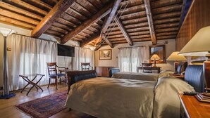 Une chambre confortable avec des poutres en bois, un grand lit, deux chaises, un bureau et une lampe.
