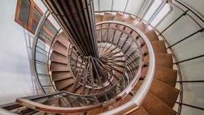 Un escalier en colimaçon avec une rampe en métal et des marches en bois.