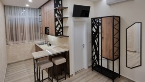 A modern kitchen with a central island, built-in shelves, and a flat-screen TV. - UP accommodation (Belgrade)