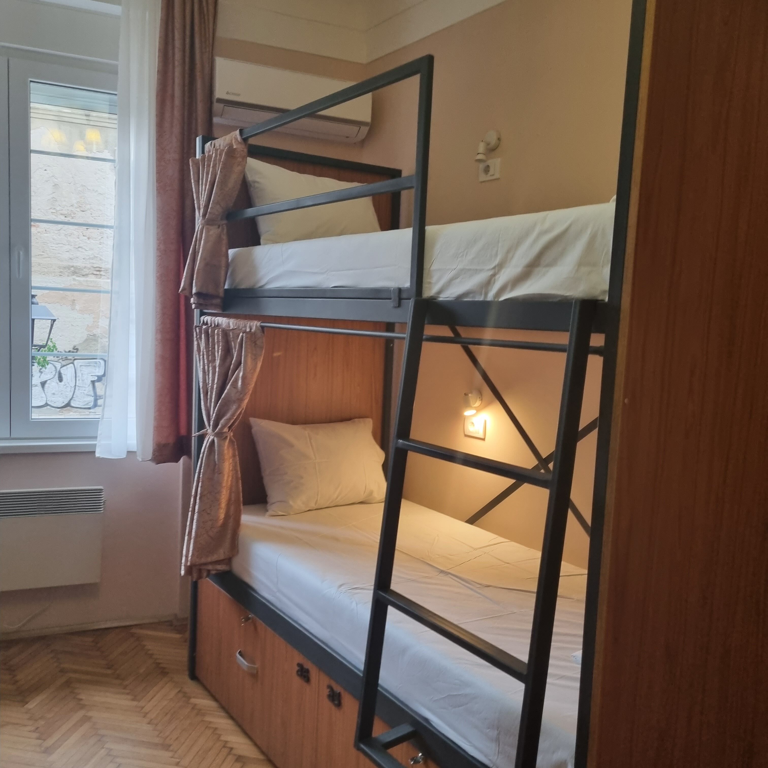 Dormitorio con literas, ventana, cortinas y un calentador.