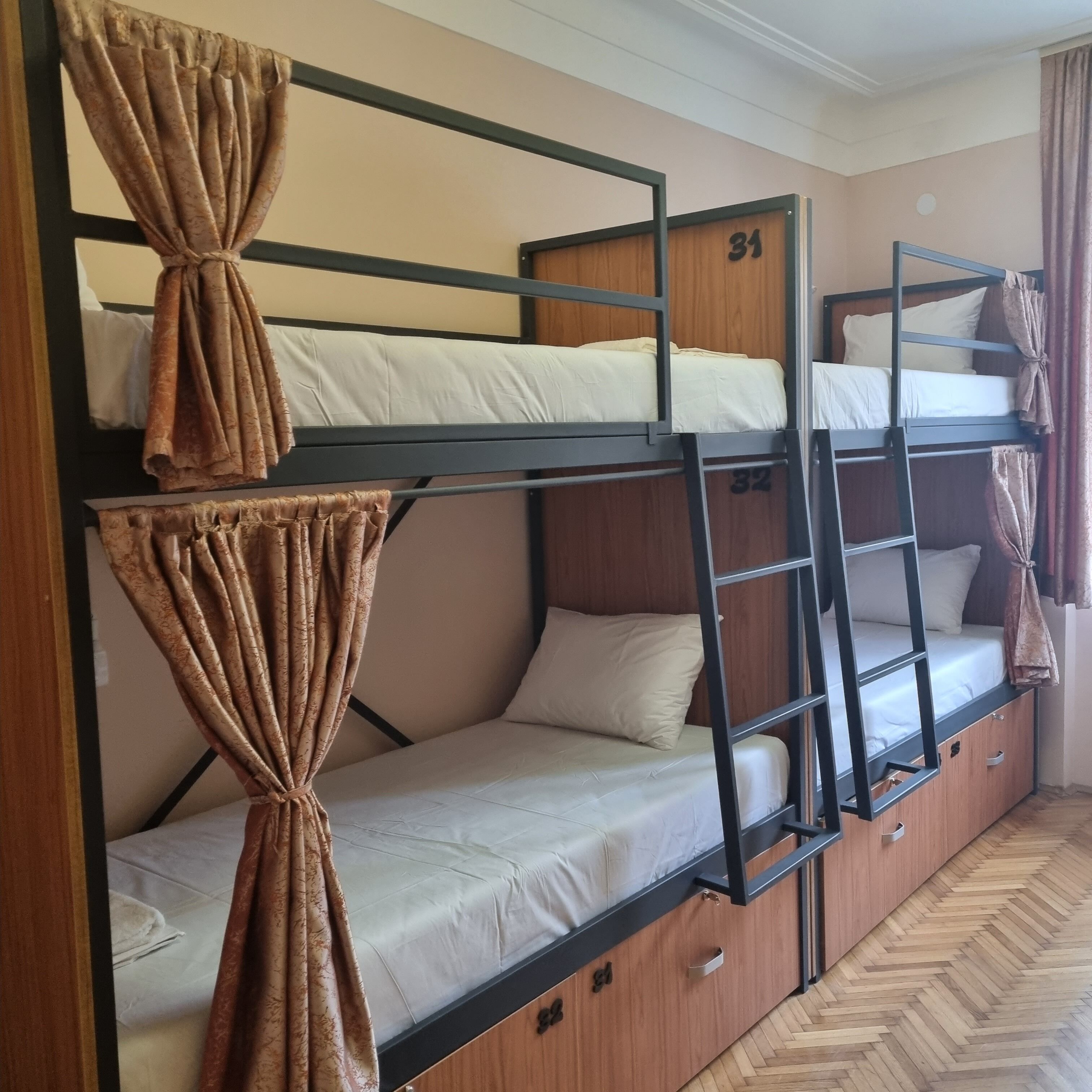 Une chambre avec des lits superposés, des murs en bois, des lits numérotés et des rideaux.