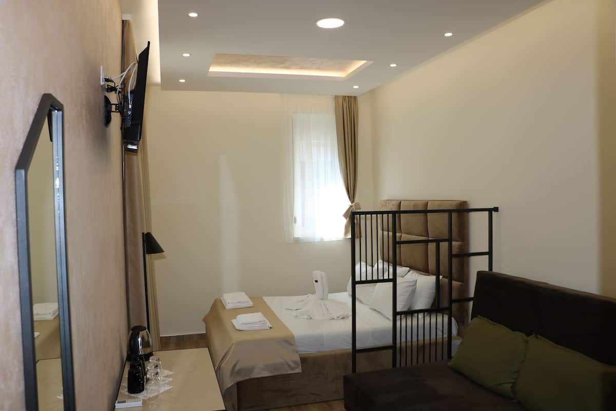 Una habitación de hotel con literas, un escritorio con lámpara, un espejo y una ventana con cortinas.