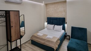 A modern bedroom with a bed, a chair, a mirror, and an air conditioning unit. - UP accommodation (Belgrade)
