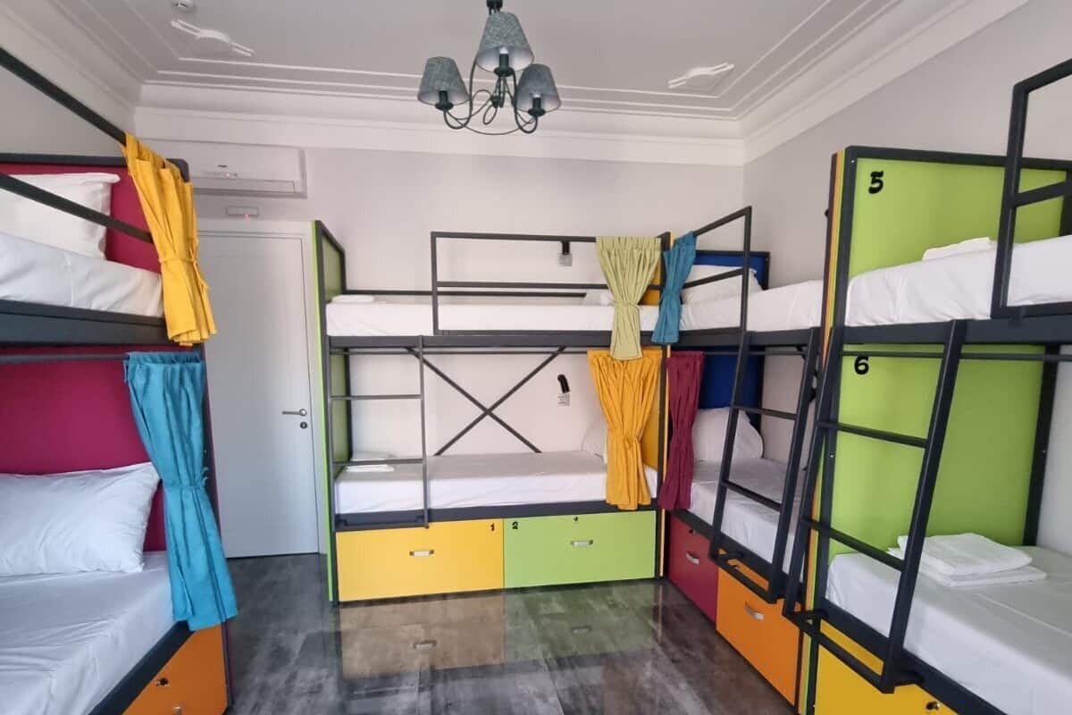 Un dormitorio con literas, un ventilador de techo y una puerta.