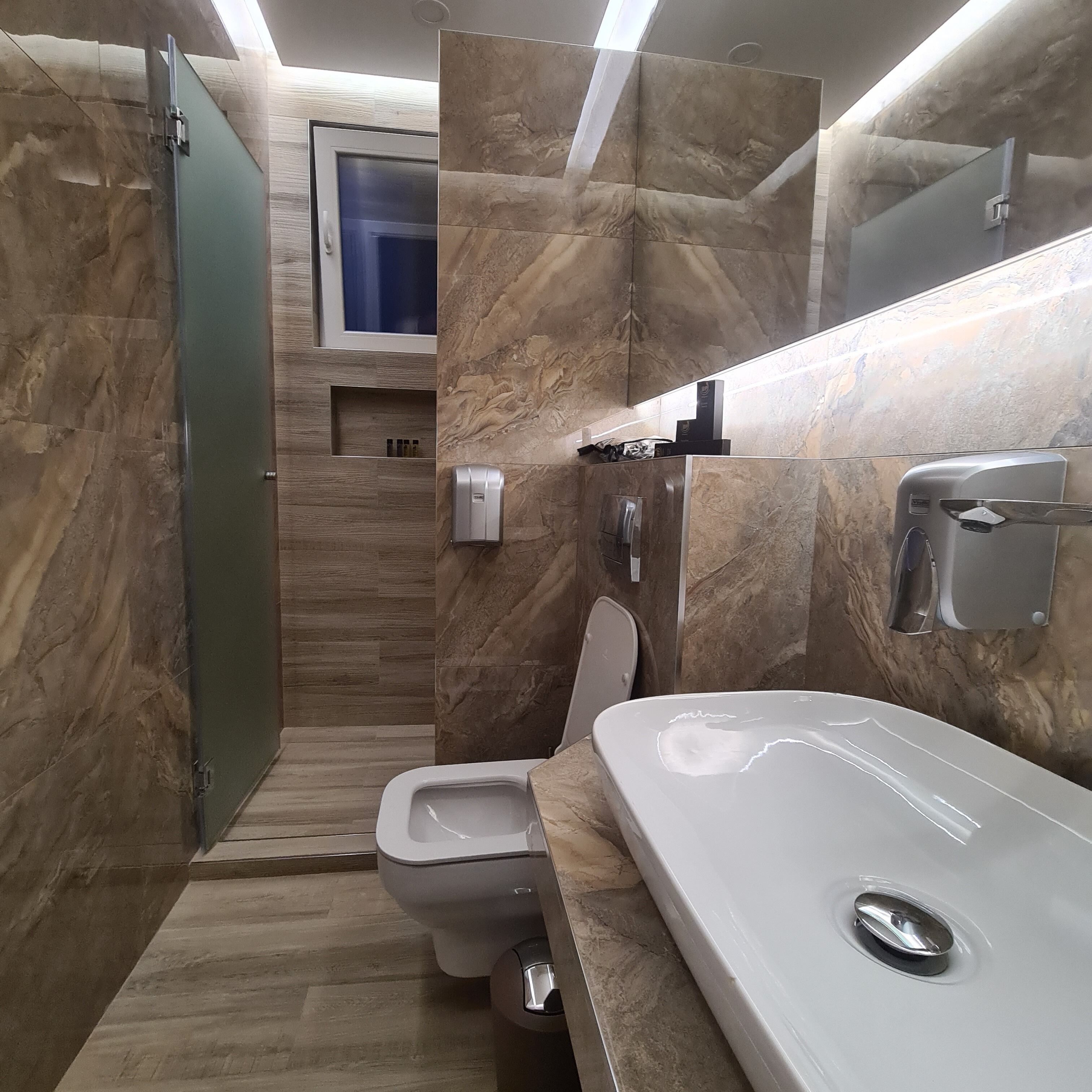 Un baño moderno con inodoro, lavamanos y zona de ducha.
