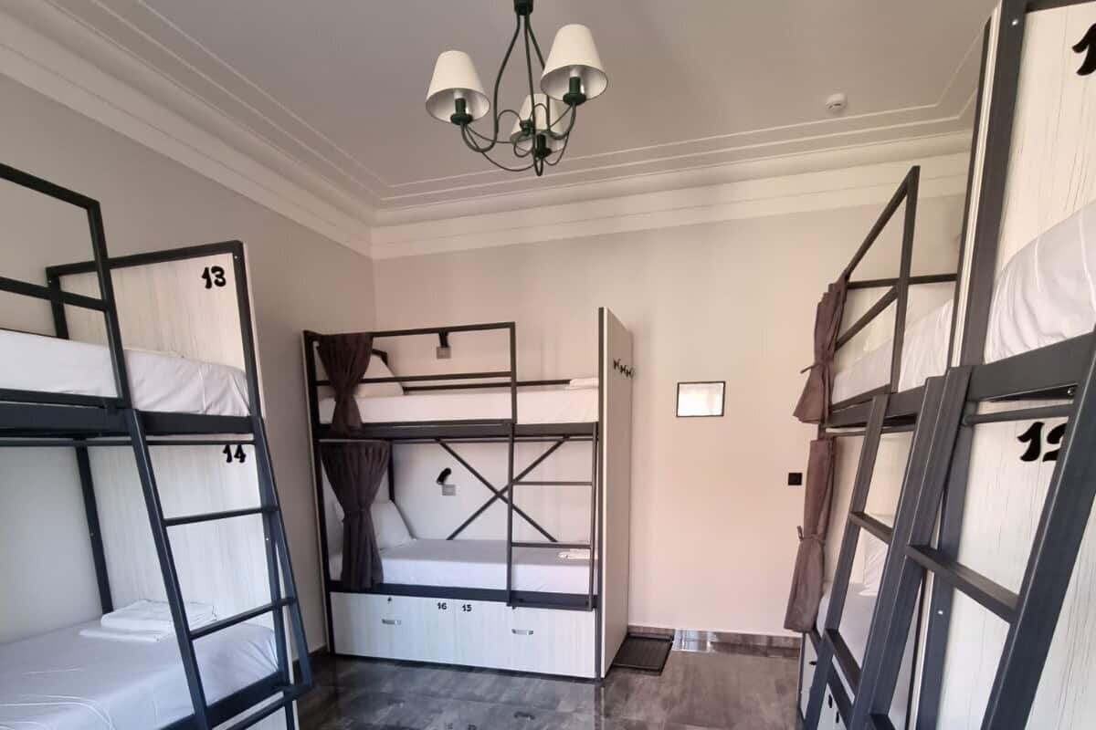 Un dormitorio con literas, un escritorio en el centro y un candelabro.