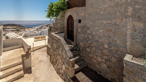 Un edificio in pietra con una porta di legno e gradini che conducono a una terrazza.