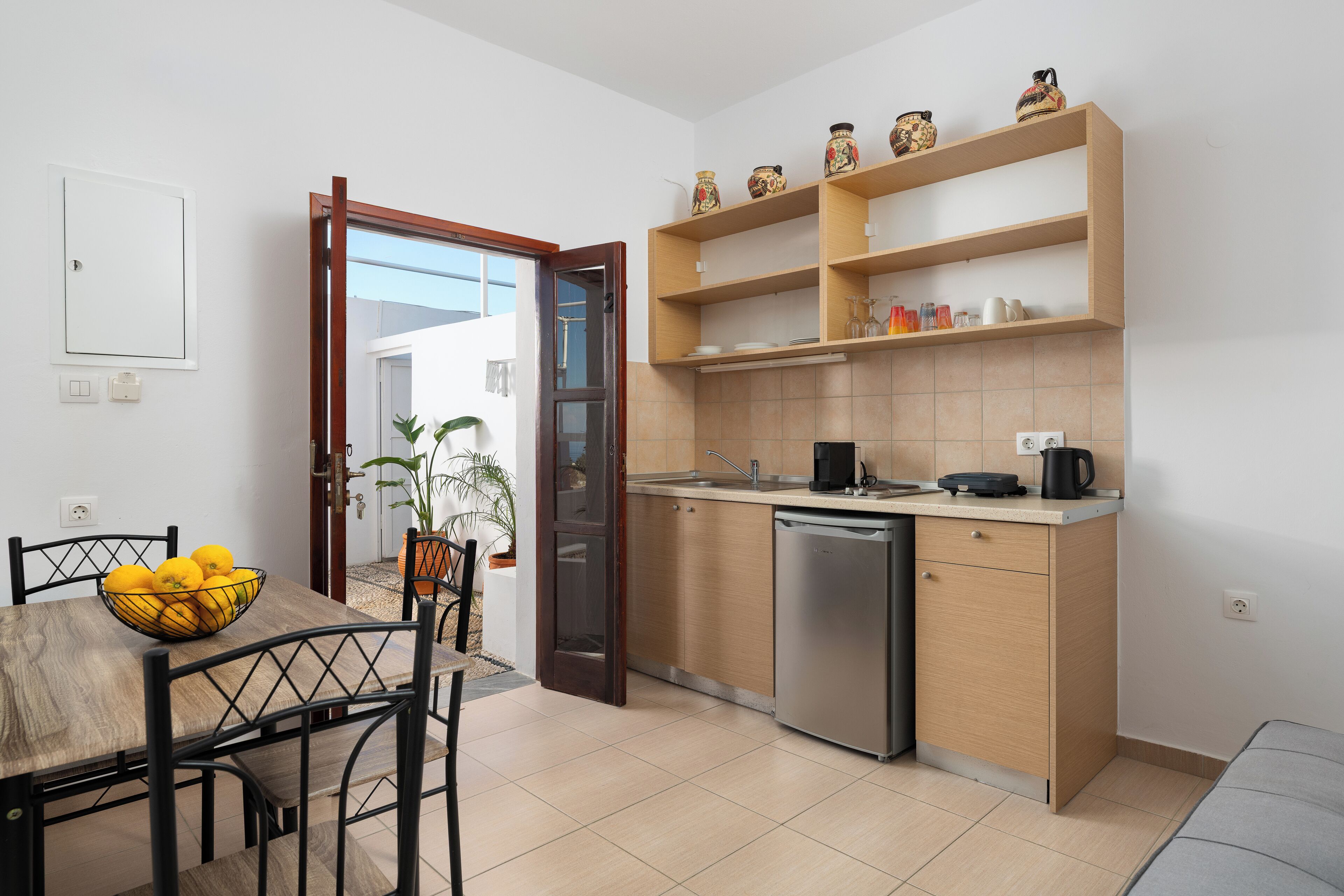 Una cocina compacta con mesa, sillas, lavavajillas y una pequeña encimera.