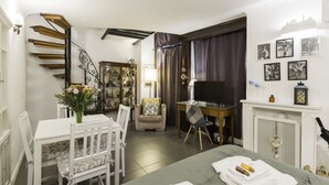 Una habitación de hotel con zona de comedor, televisión, chimenea y escalera.