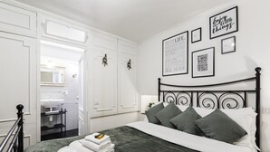 Un dormitorio ordenado con cama, almohadas y mesita de noche.