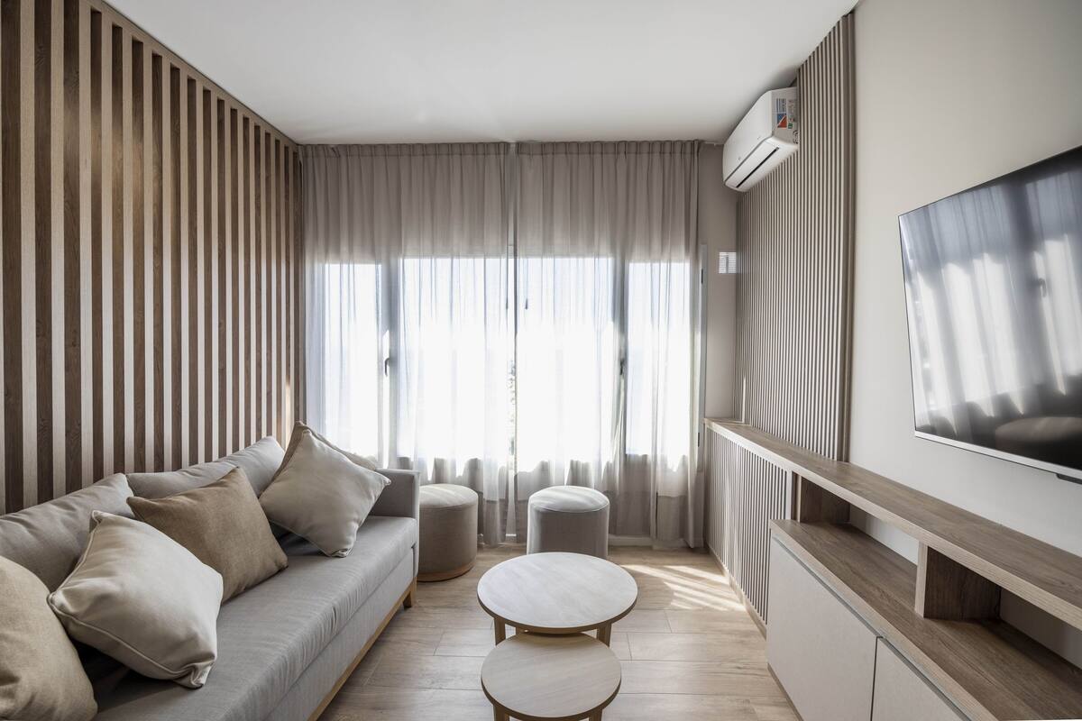 Uma sala de estar moderna com um sofá, um banquinho e uma mesa de centro redonda.