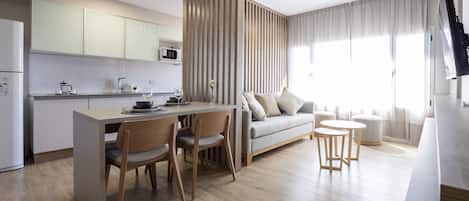 A modern kitchen with a dining area, a sofa, and a TV.
