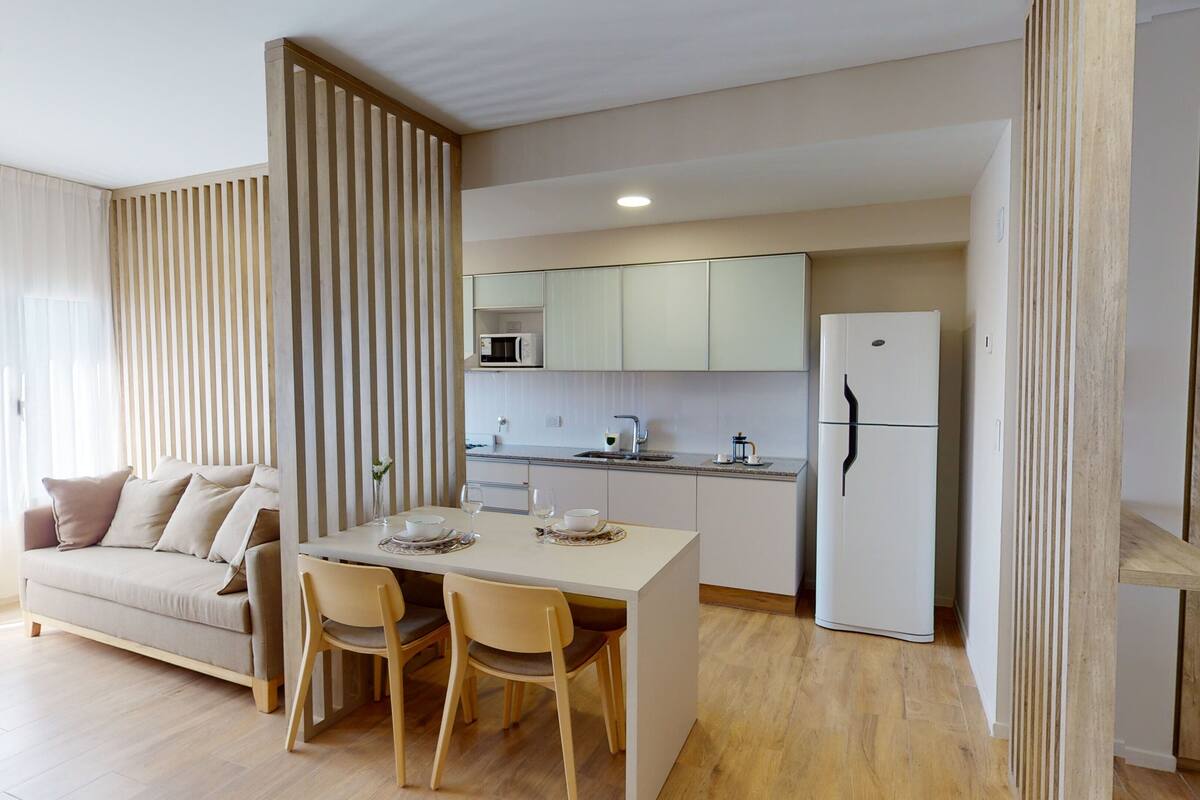 Uma cozinha moderna com área de jantar, sofá e piso de madeira.