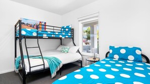 A bunk bed room with a polka dot bedspread, a view of the street through a window, and a small table with a lamp. - Island Vibes Retreat on the Cowes Esplanade (Cowes)