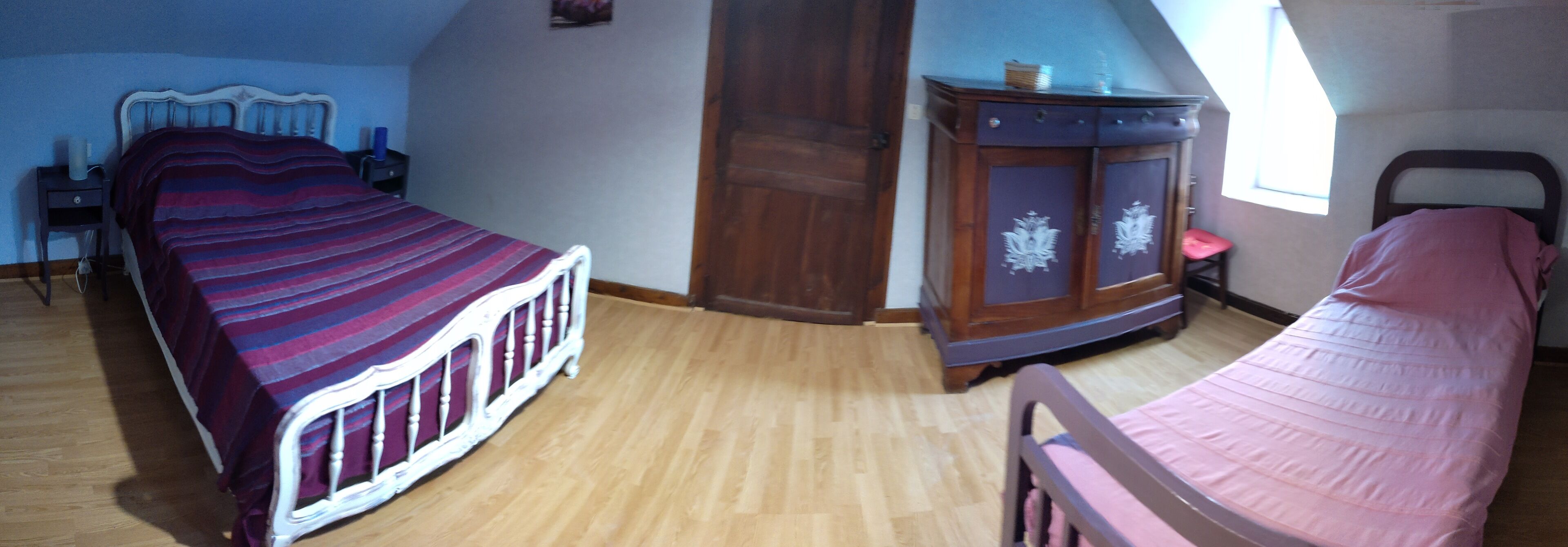 Una camera da letto con due letti, un armadio in legno, un tavolino e una finestra.